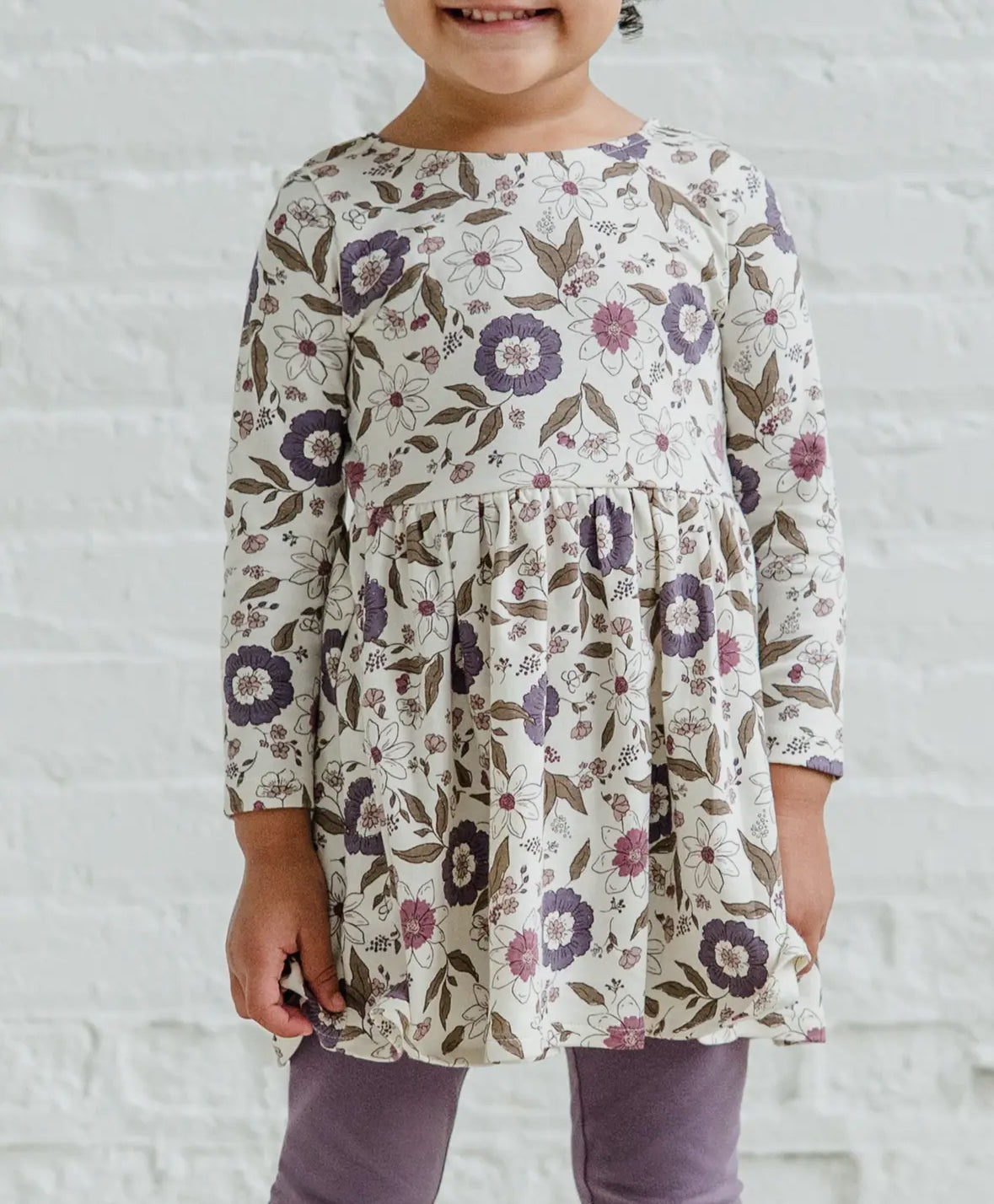 Child wearing a floral dress with a white background