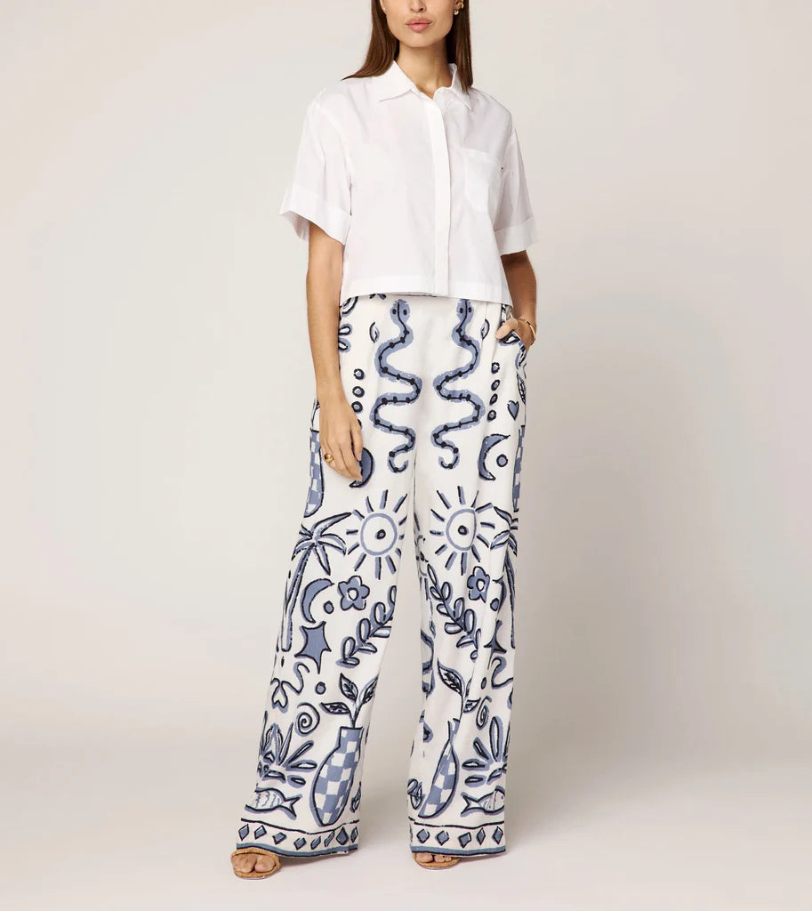 Person wearing a white shirt and patterned pants on a plain background