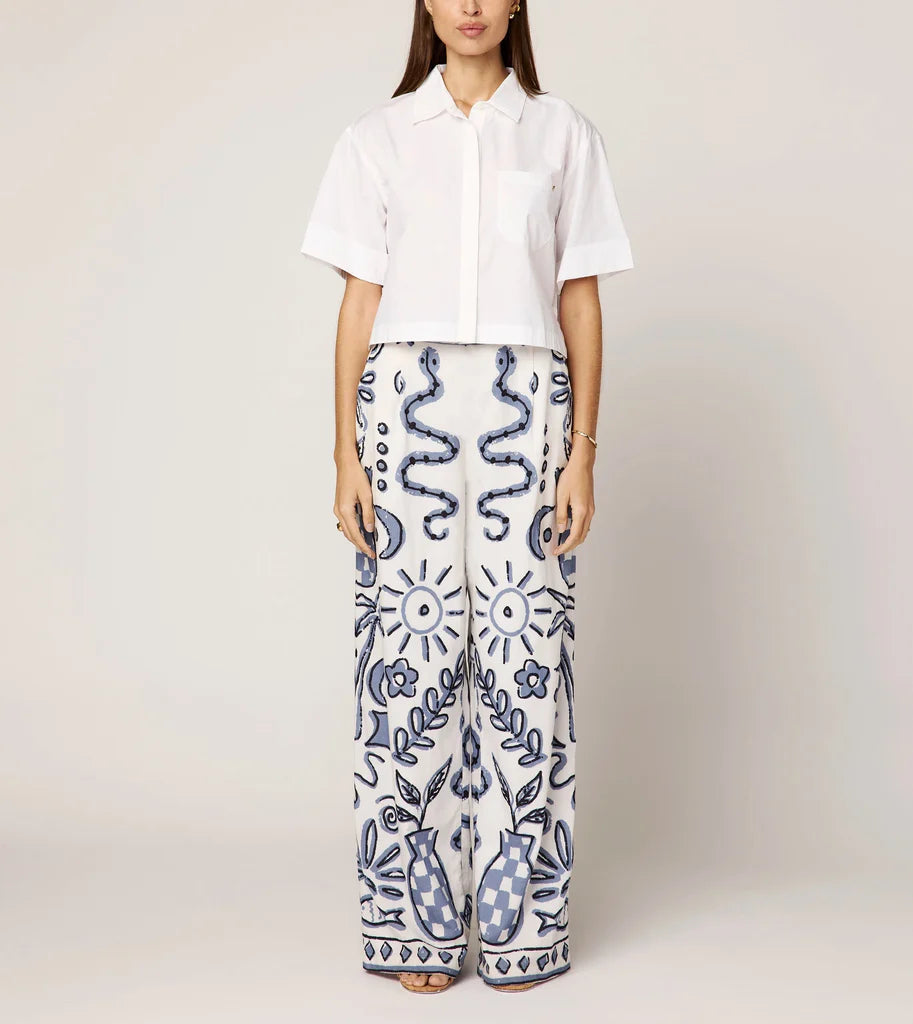 Person wearing a white shirt and patterned pants on a plain background