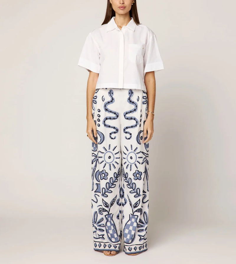 Person wearing a white shirt and patterned pants on a plain background