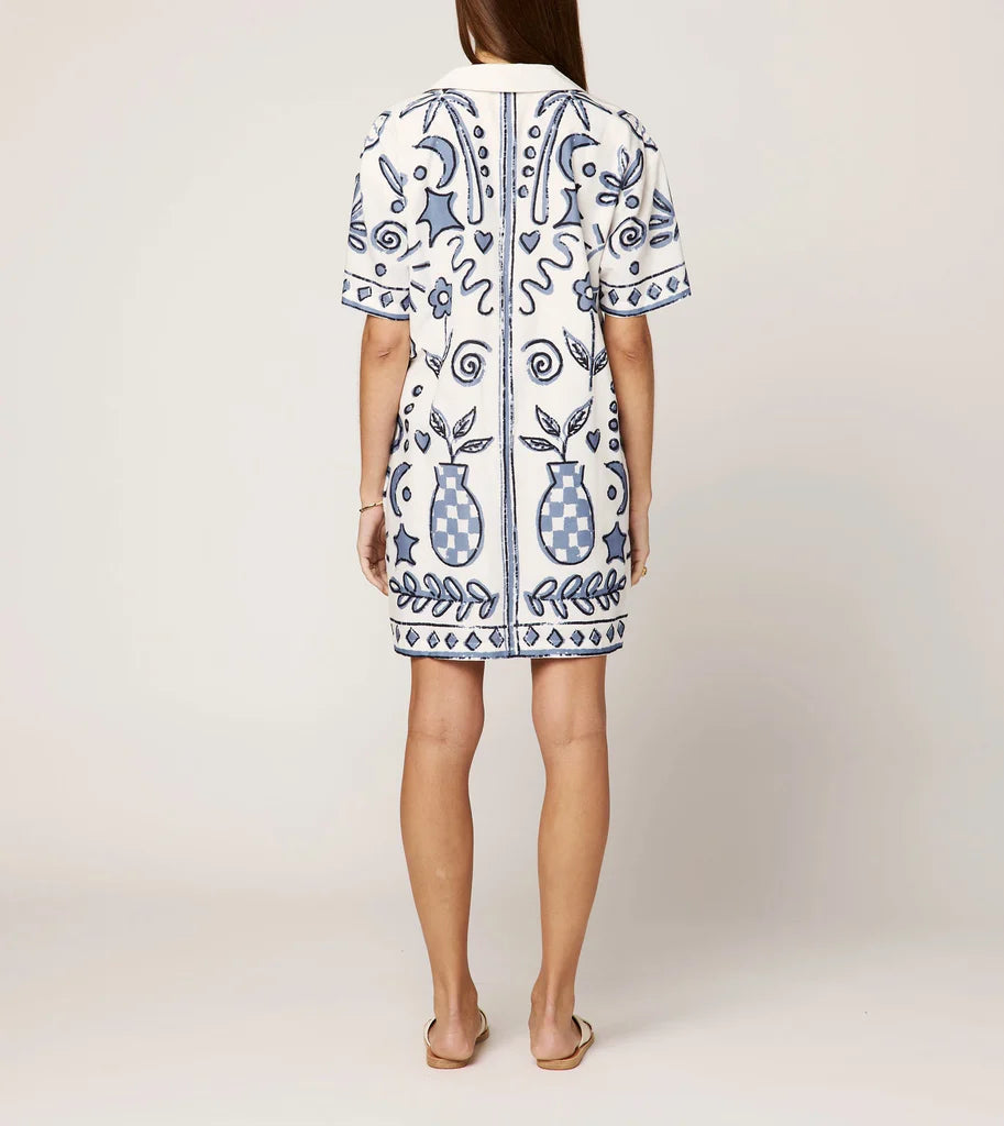 White dress with blue floral patterns on a plain background