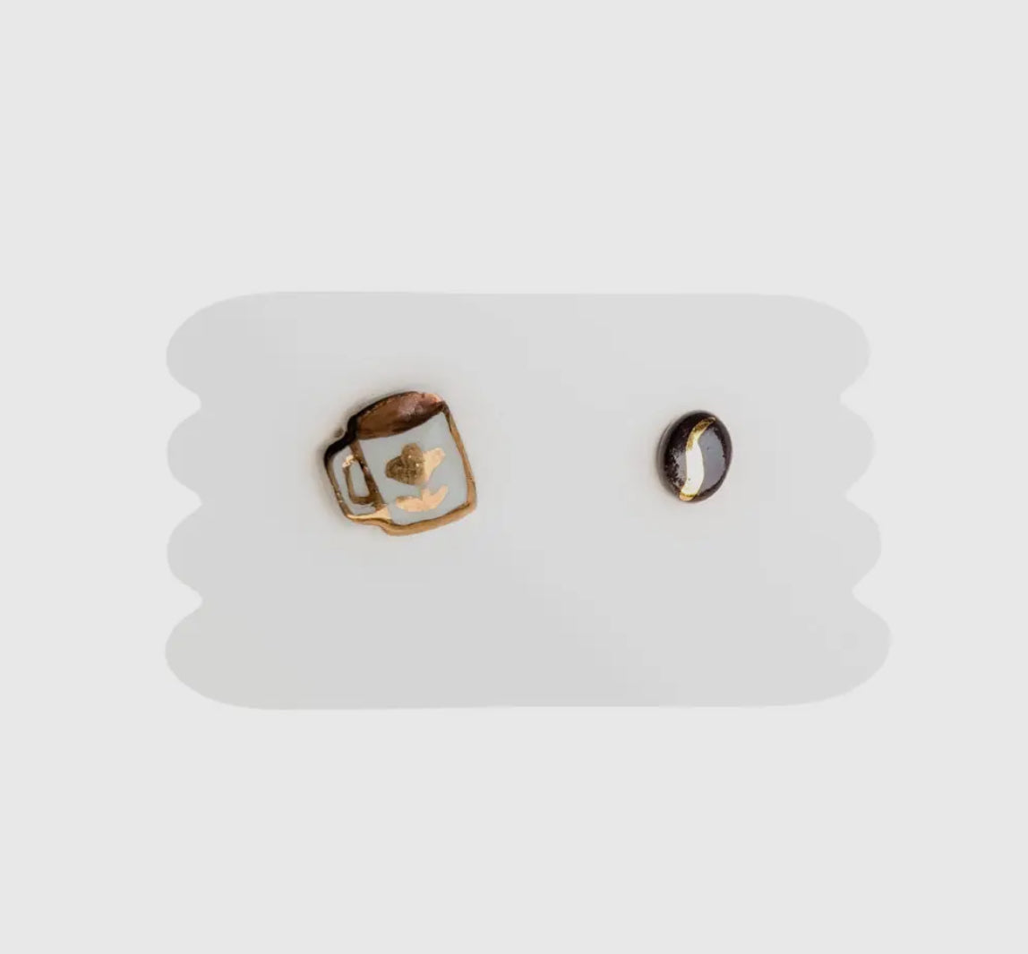 Pair of mismatched mug and coffee bean earrings on a white display card. 