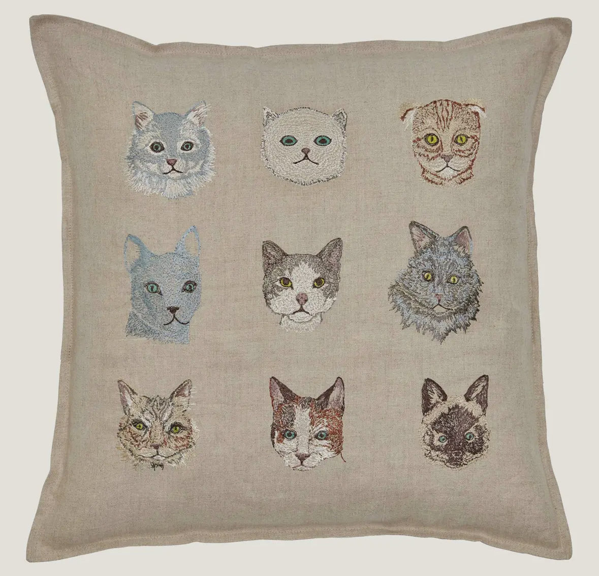 Pillow with embroidered cat faces on a beige background