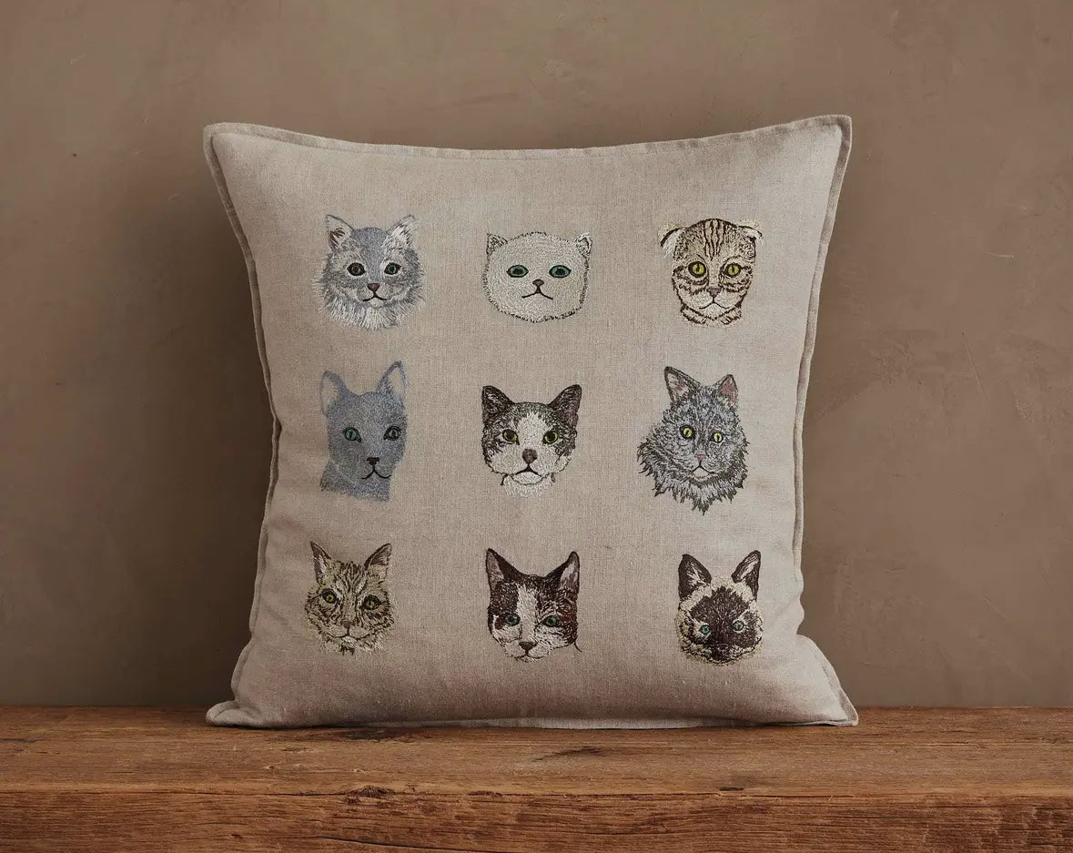 Pillow with cat illustrations on a wooden surface against a brown background