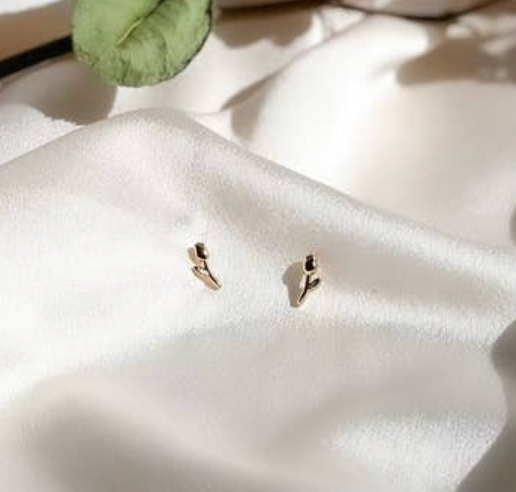 Small gold earrings on a white fabric surface