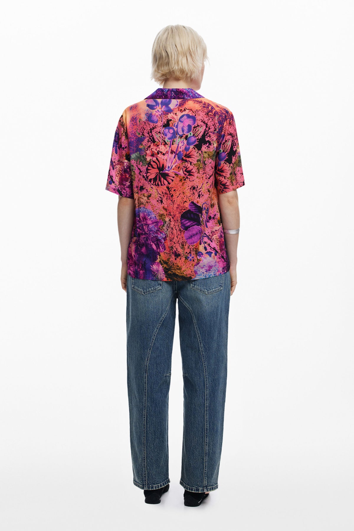 Person wearing a colorful floral shirt and blue jeans on a white background