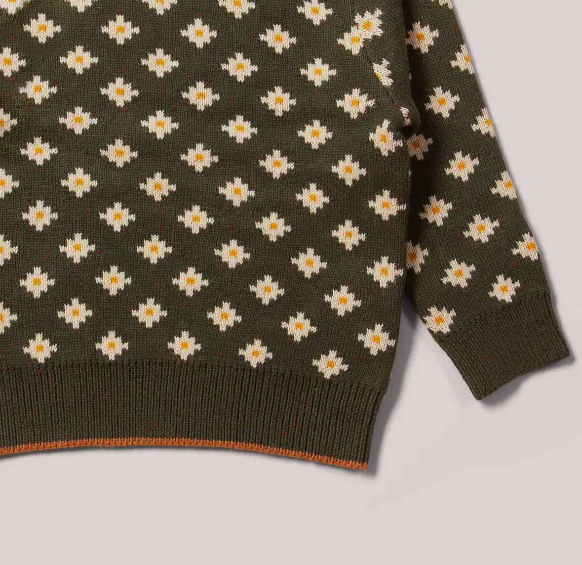 Green sweater with white daisy pattern on a light gray background