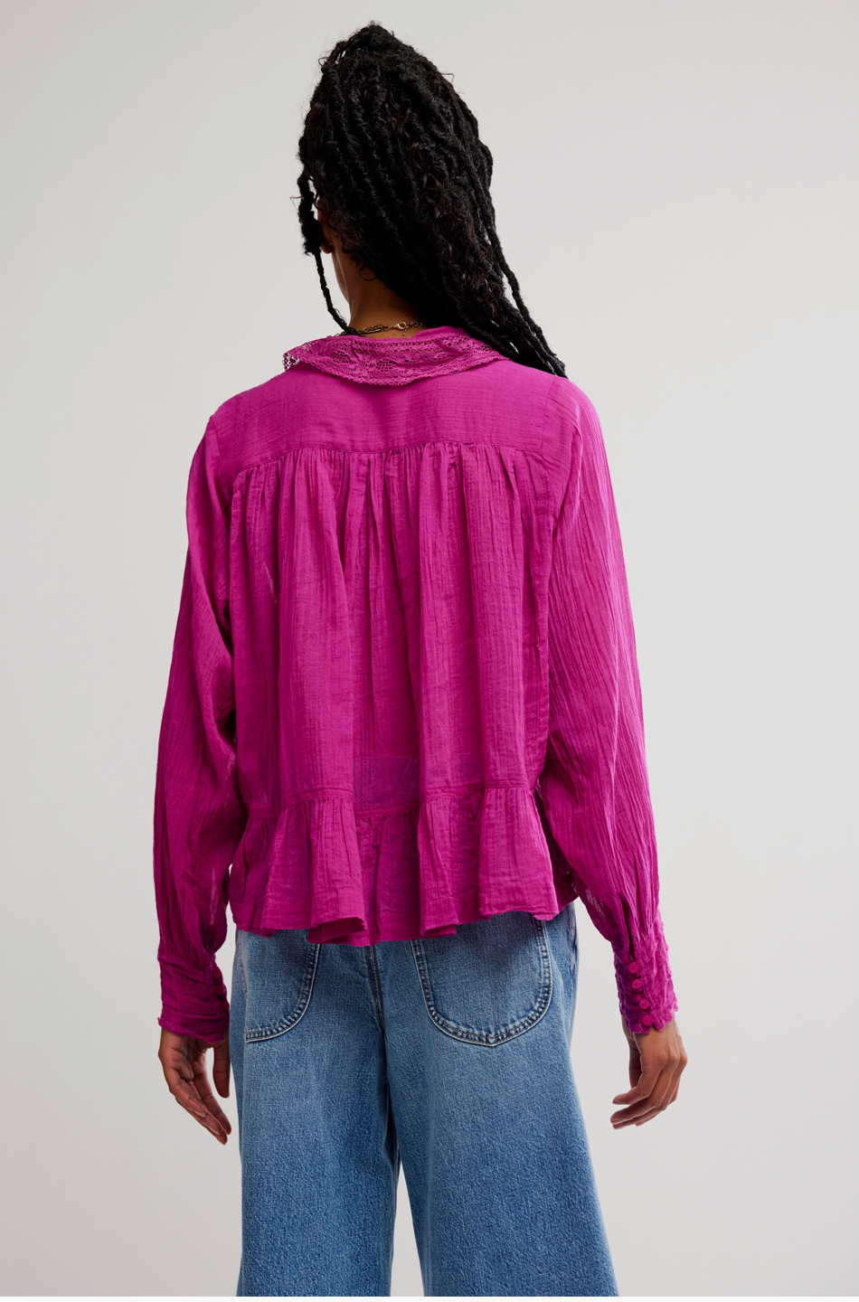 Person wearing a pink blouse and blue jeans on a plain background