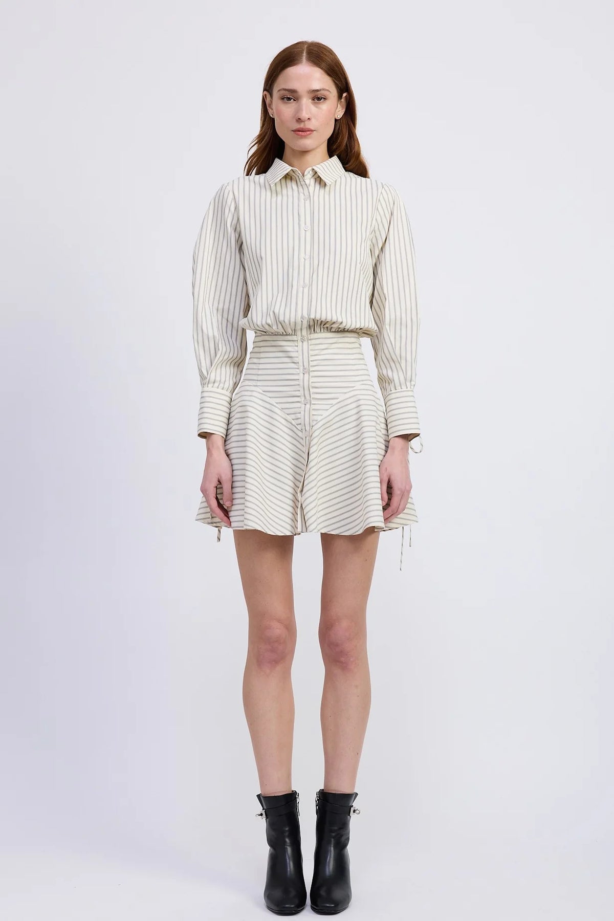 Woman wearing a striped shirt and skirt with black boots on a white background