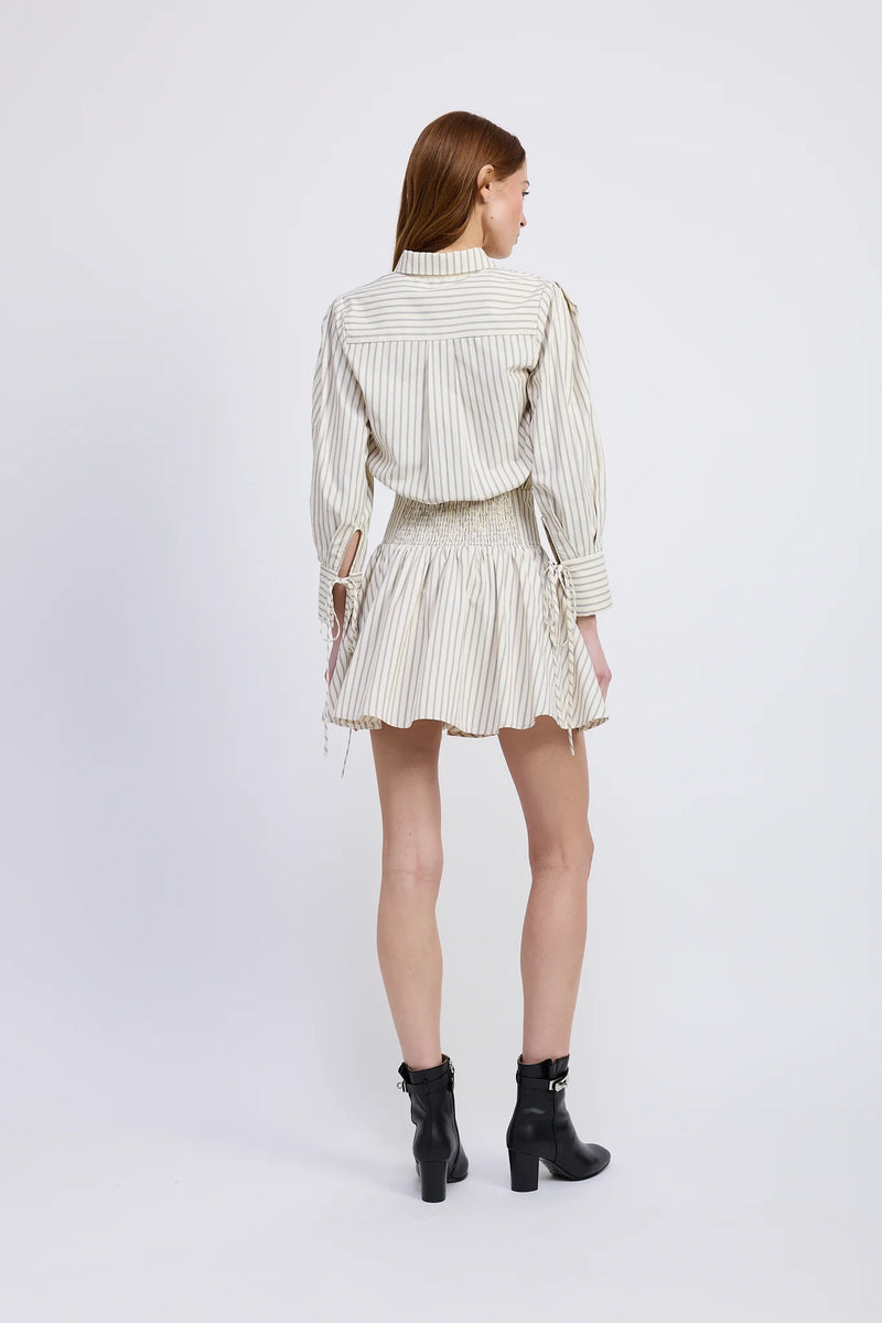 Woman wearing a striped shirt and skirt set with black boots on a white background