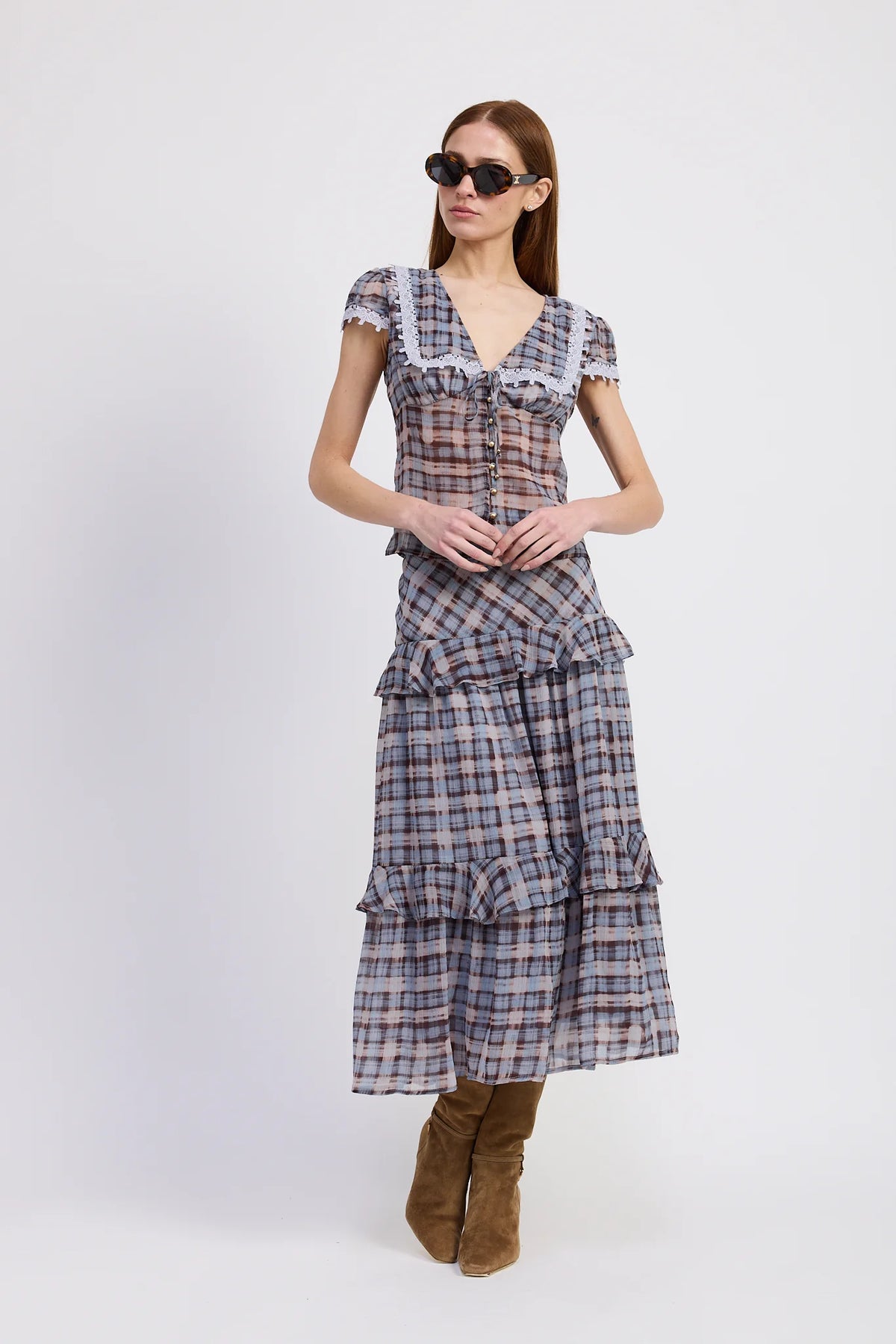 Woman wearing a plaid dress with ruffled layers on a white background