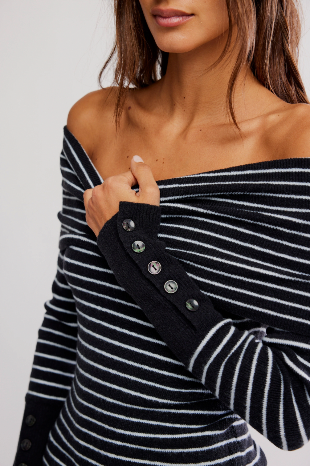 Black and white striped off-shoulder top with button details on a plain background