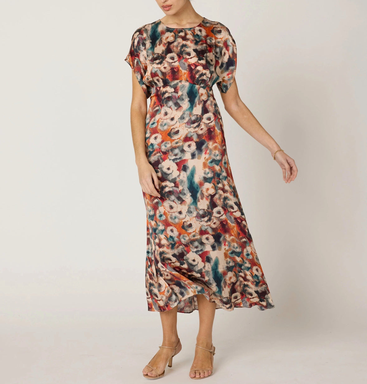 Woman wearing a colorful floral dress on a plain background