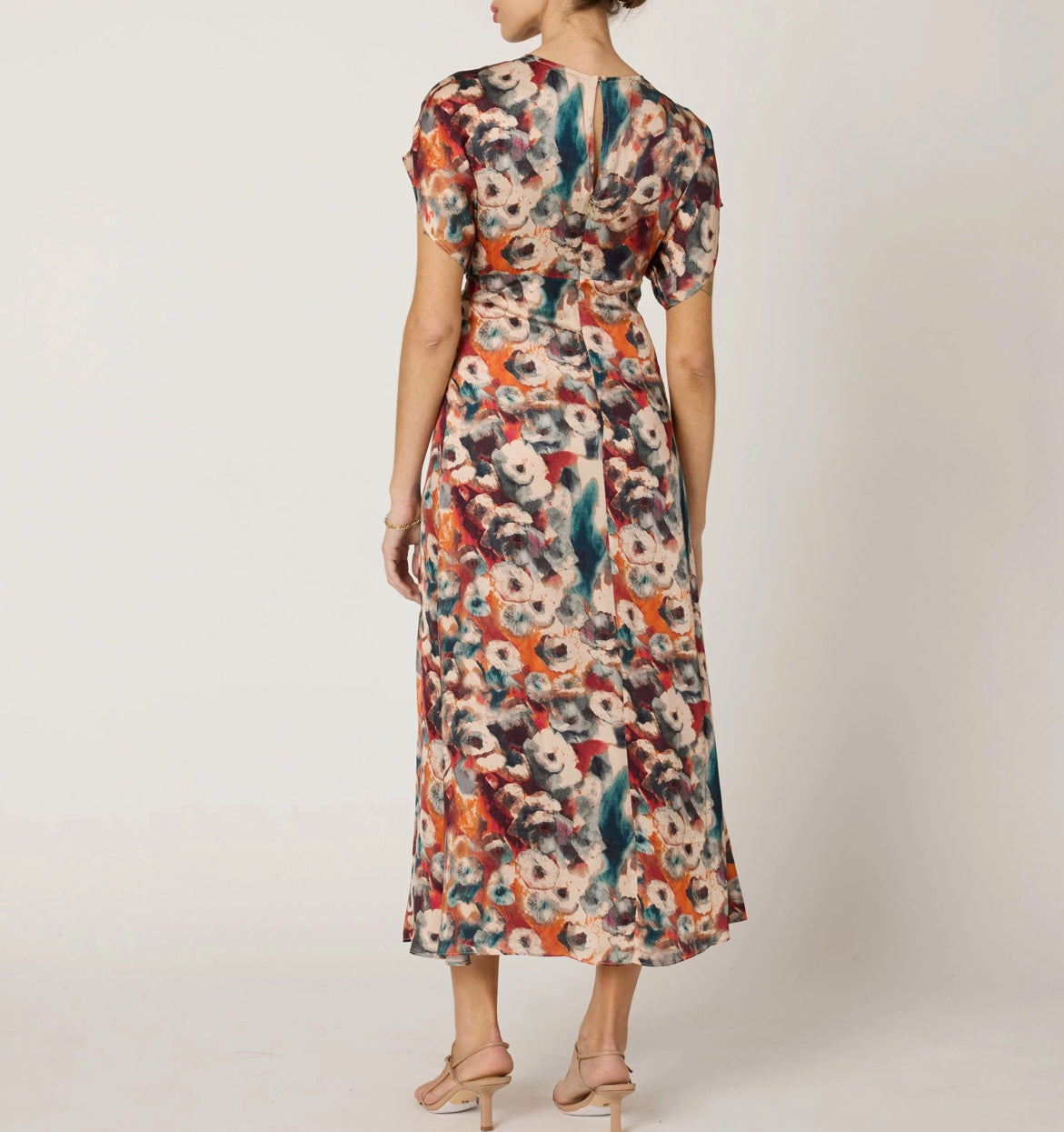 Woman wearing a colorful floral dress on a plain background