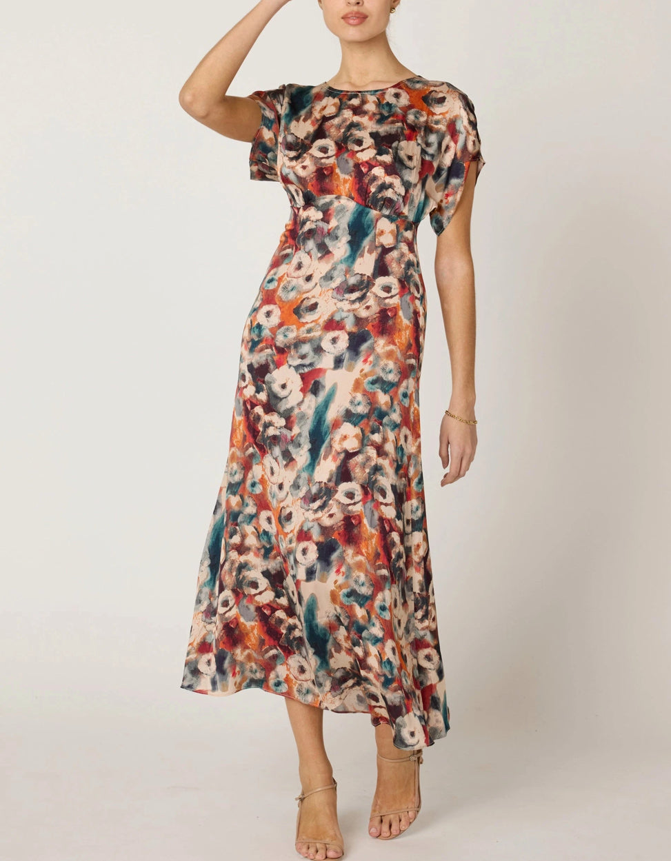 Woman wearing a colorful floral dress on a plain background