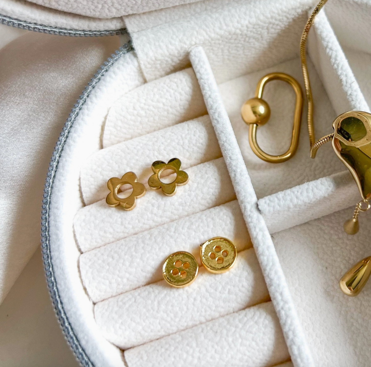 Gold earrings displayed in a jewelry box on a white background