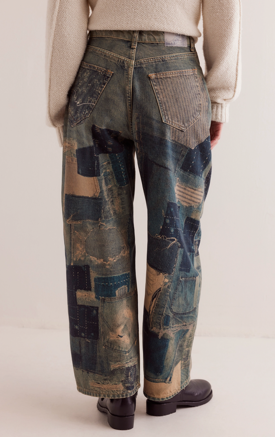 Person wearing patchwork jeans on a plain background