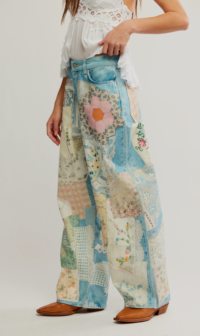 Person wearing a pair of wide-leg pants with floral and patchwork patterns on a white background