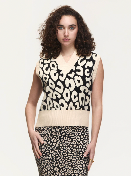 Woman wearing a sleeveless top with leopard print design on a plain background