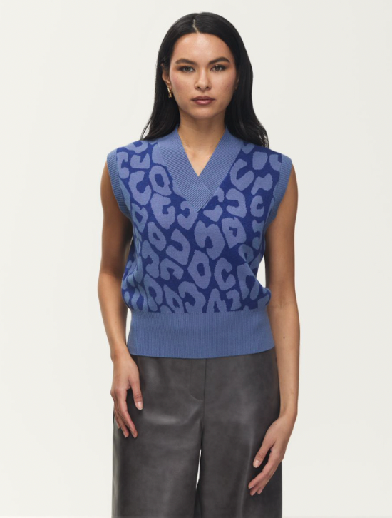 Woman wearing a blue patterned sleeveless top and gray pants on a white background