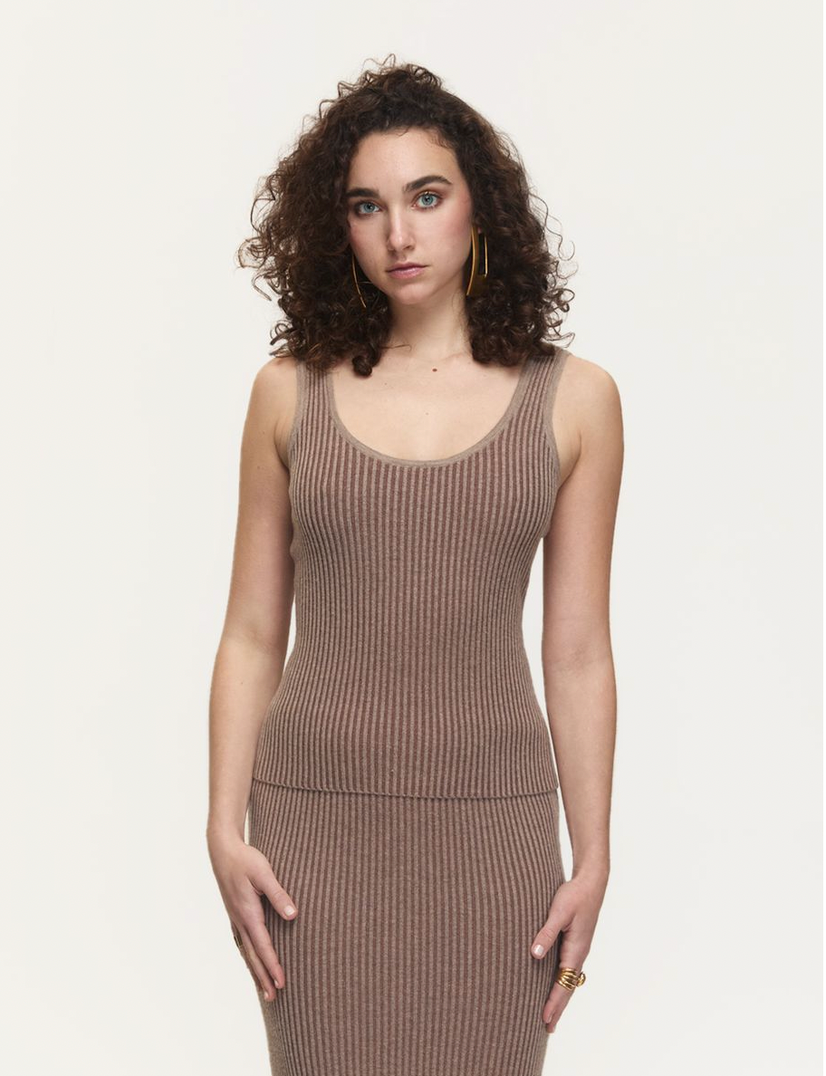 Woman wearing a brown ribbed dress against a white background