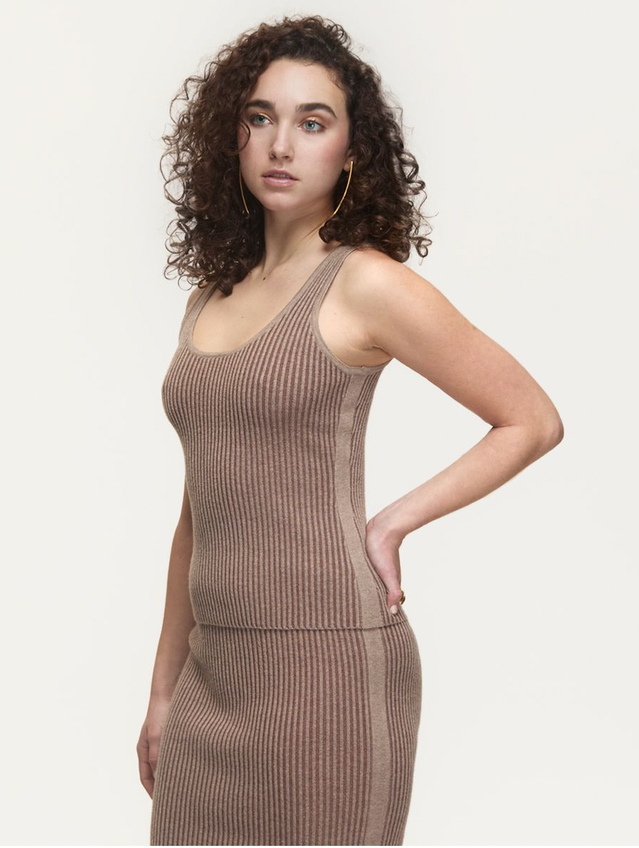 Woman wearing a ribbed brown top against a plain background