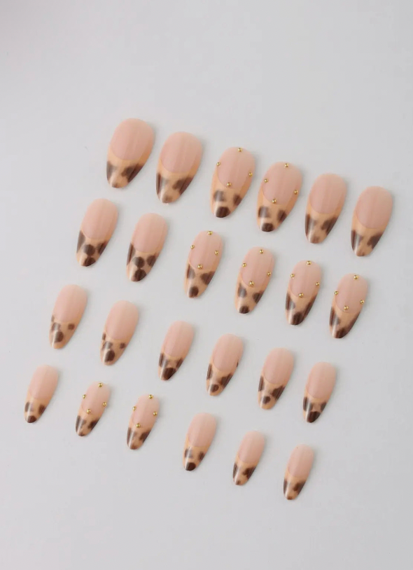 Row of beige press-on nails with brown tips on a light gray background