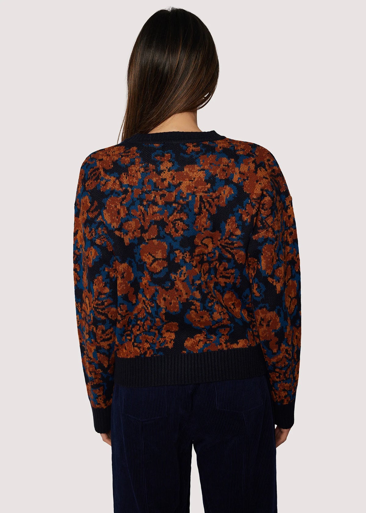 Person wearing a floral-patterned sweater on a plain background
