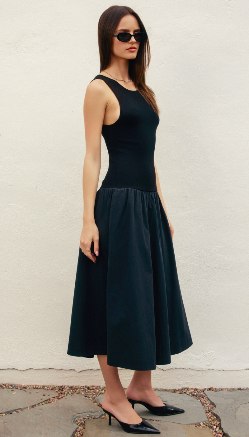 Woman wearing a black sleeveless dress against a plain background