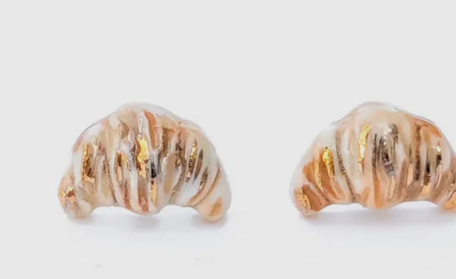 Pair of gold and white shell-shaped earrings on a light gray background