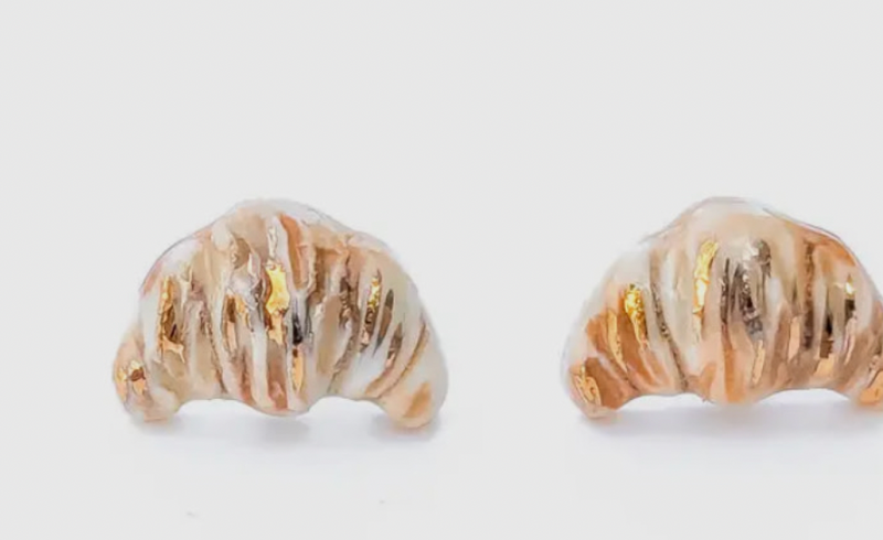 Pair of gold and white shell-shaped earrings on a light gray background