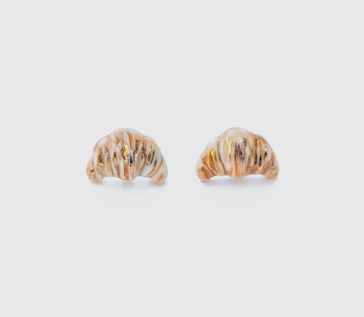 Pair of gold shell-shaped earrings on a light gray background