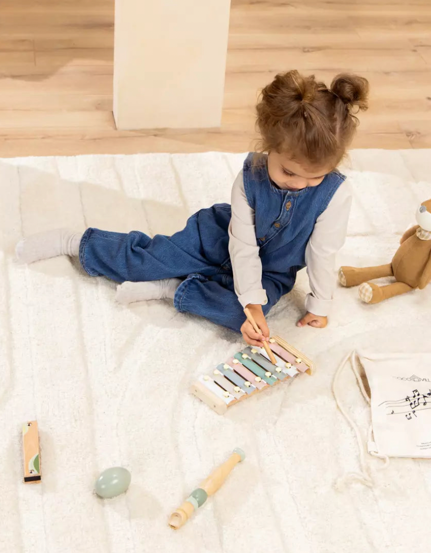Child playing with musical instruments on a light-colored rug