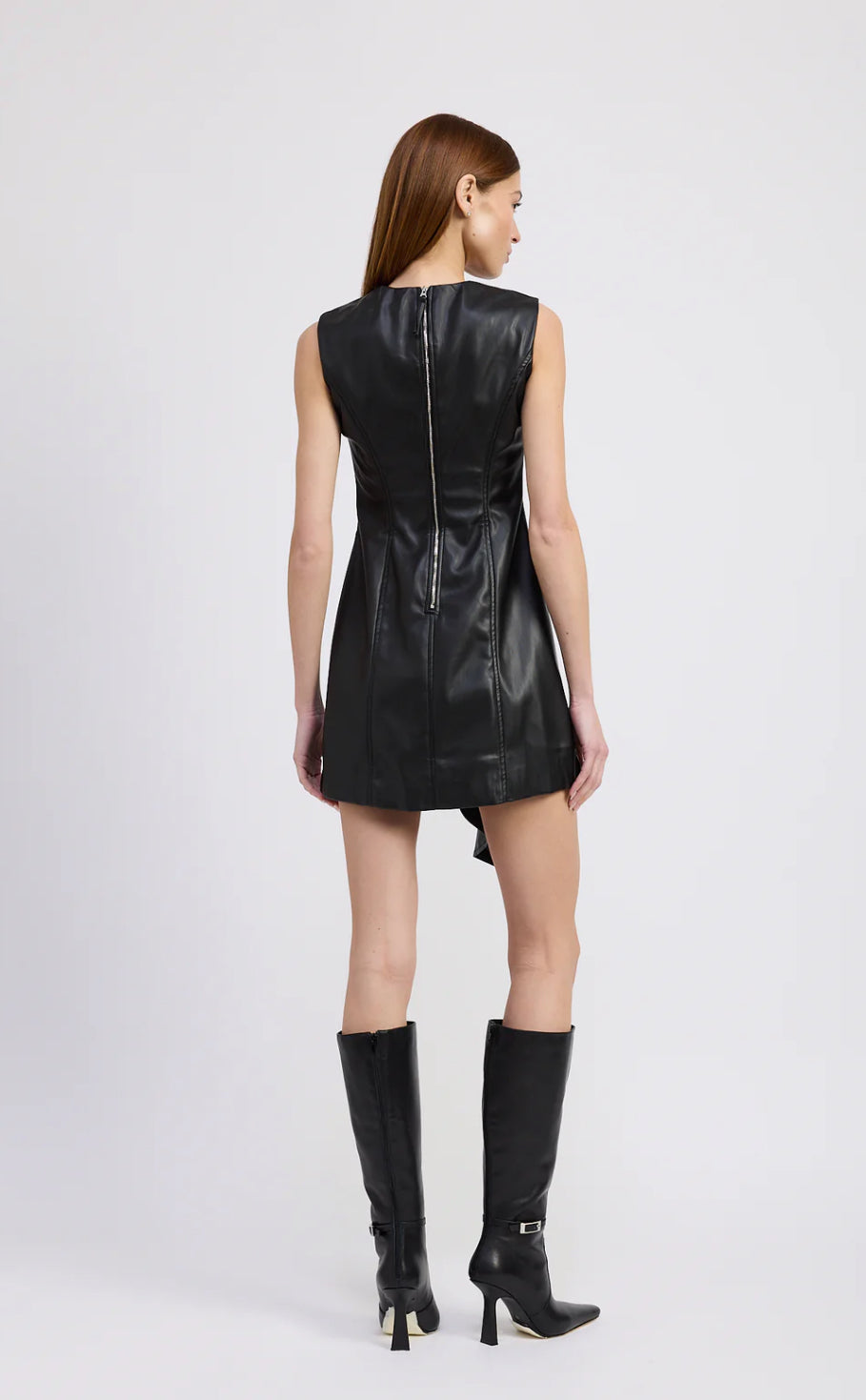 Woman wearing a black leather dress and boots on a white background