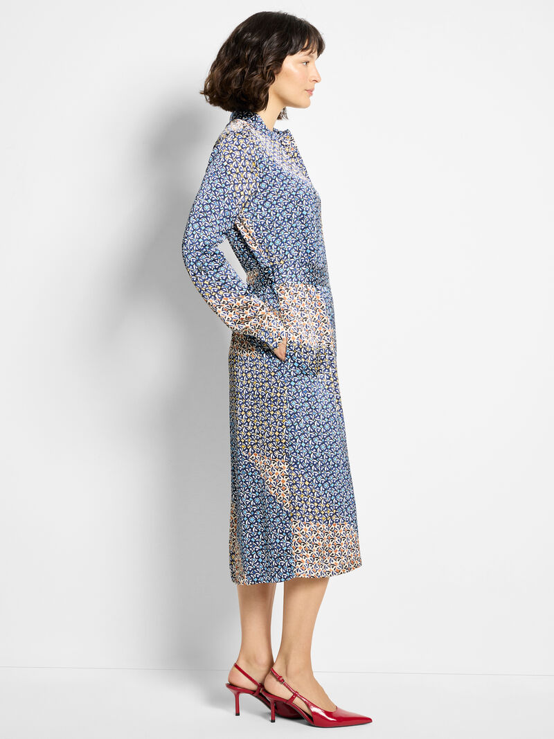 Woman wearing a blue patterned dress with a white background