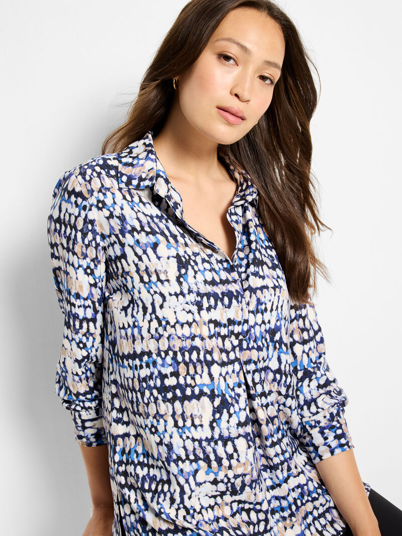 Woman wearing a patterned blouse against a plain background
