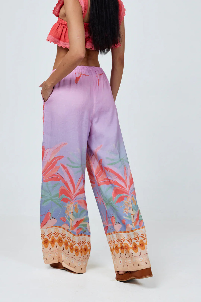 Person wearing a colorful outfit with a pink top and patterned pants on a white background