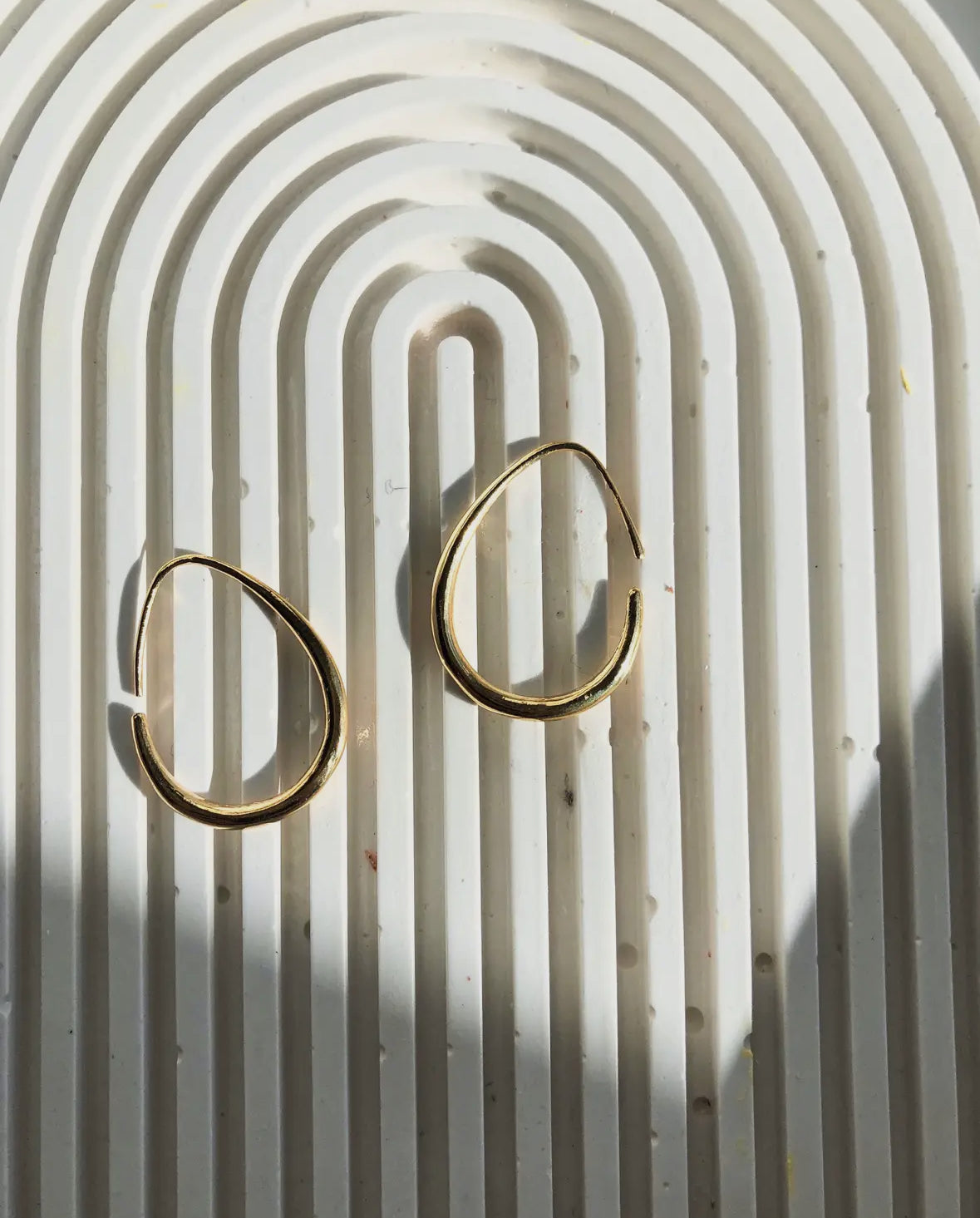 Gold hoop earrings on a textured white surface