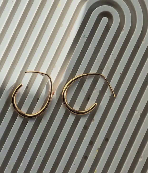 Gold hoop earrings on a textured white surface