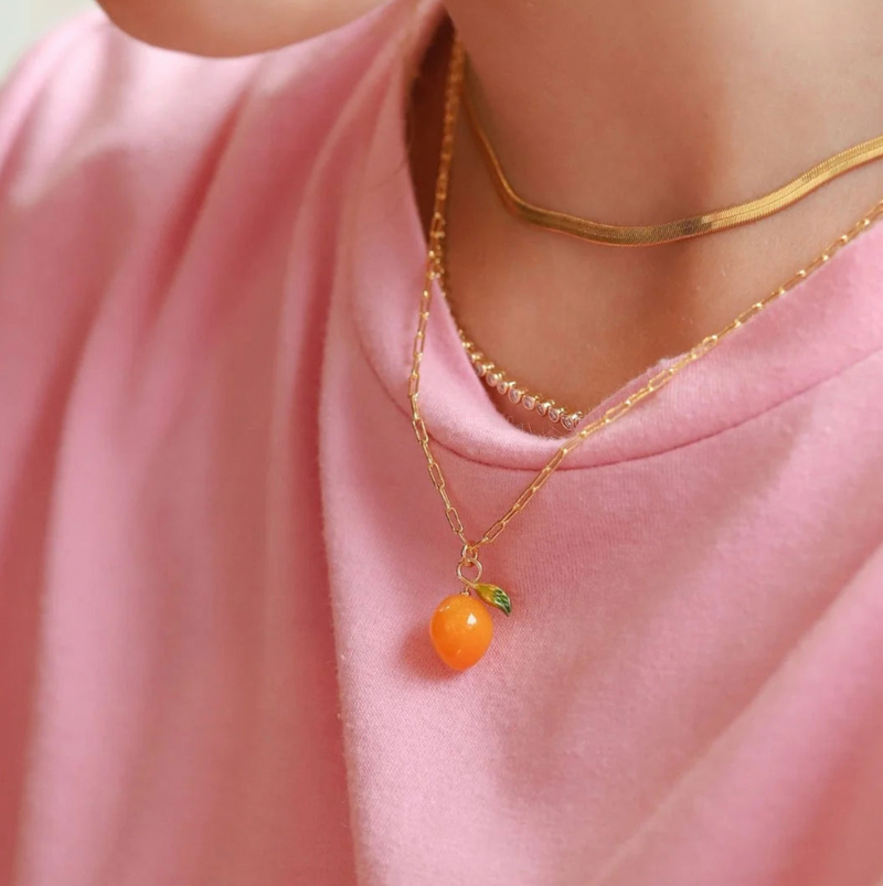 Necklace with a small orange pendant on a pink shirt
