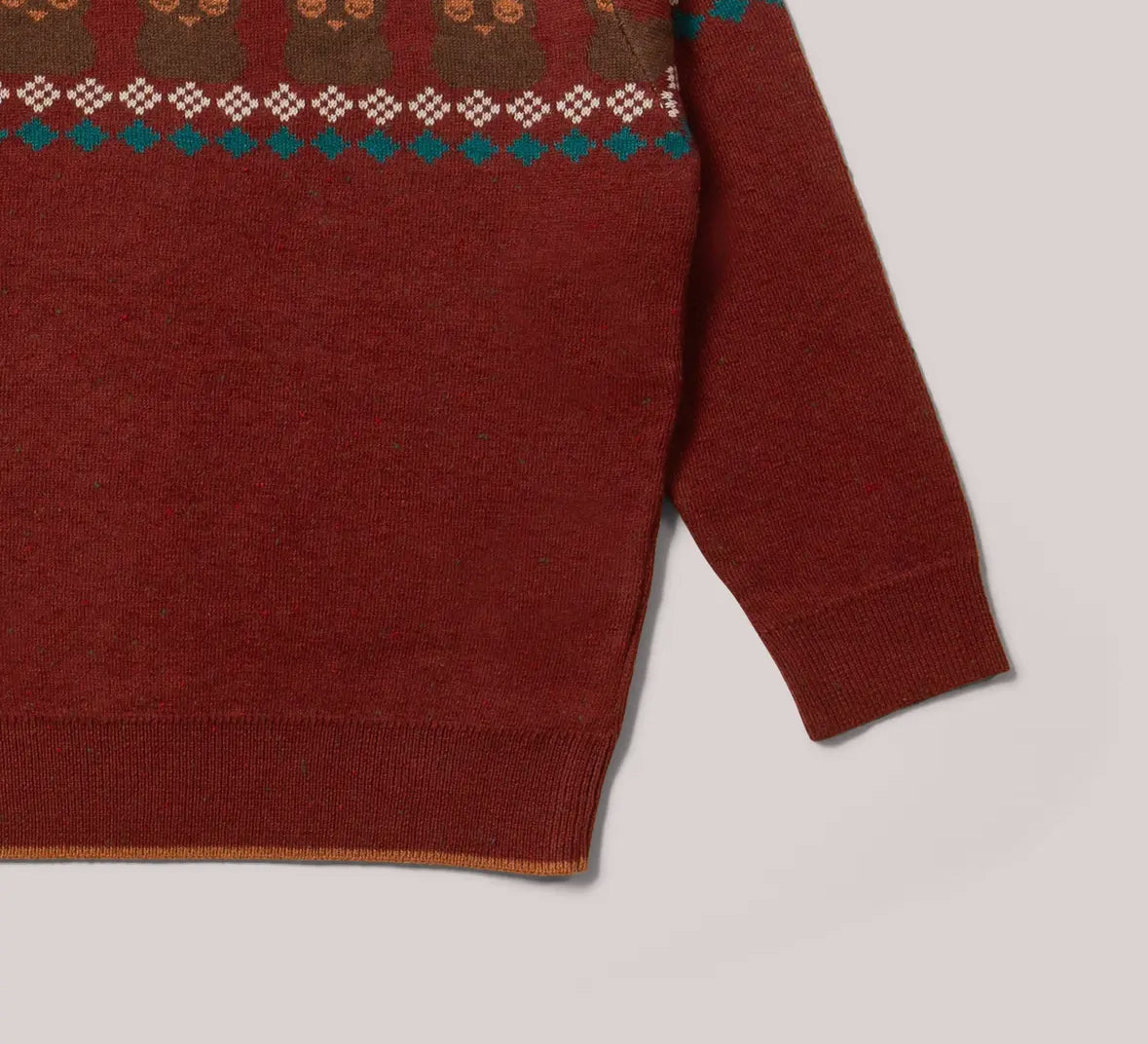 Close-up of a red sweater with patterned trim on a light gray background