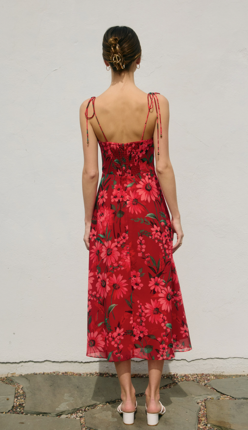 Woman wearing a red floral dress against a plain background