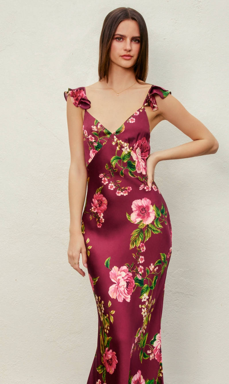 Woman wearing a burgundy floral dress against a plain background