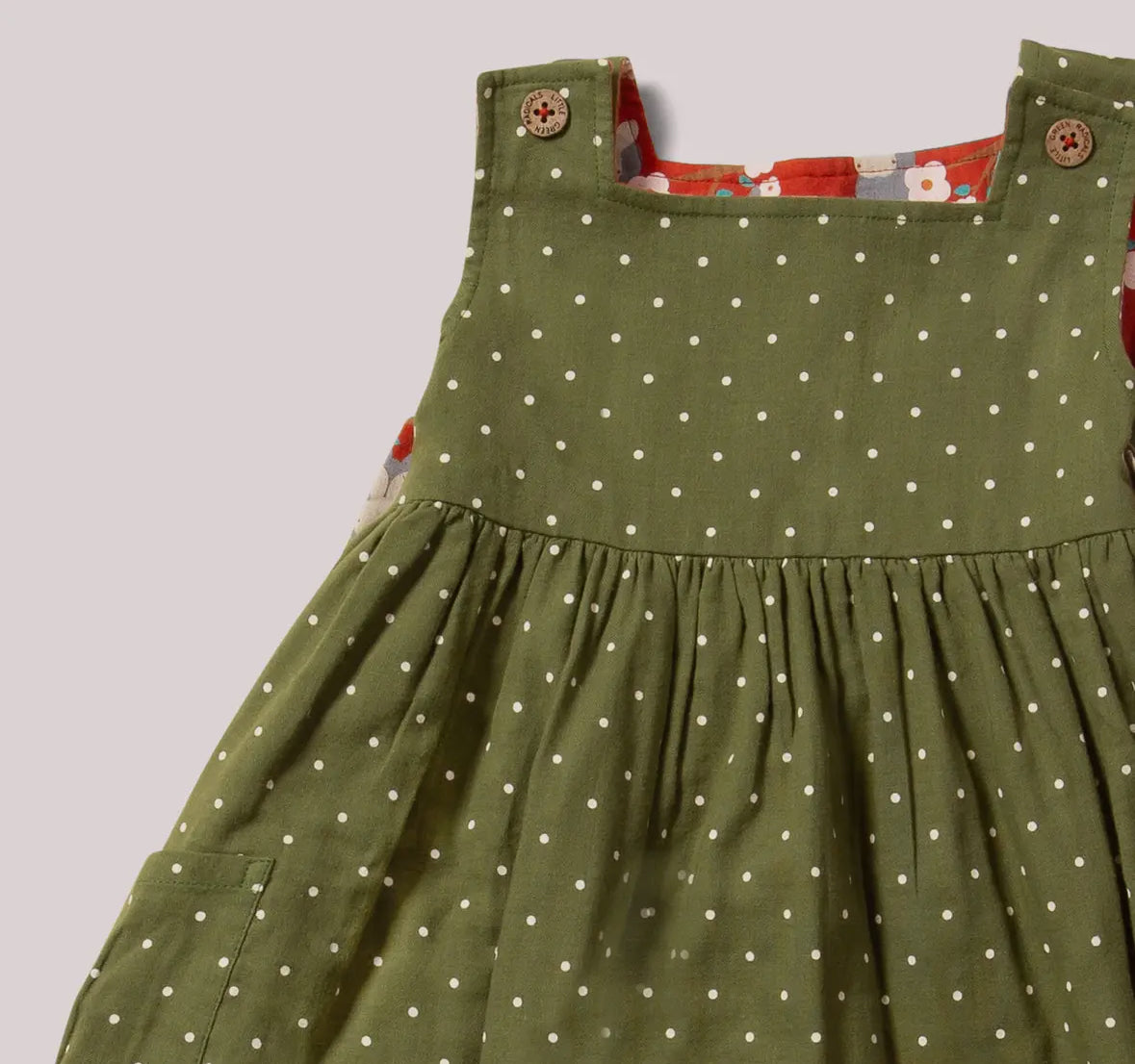 Green dress with white polka dots on a plain background