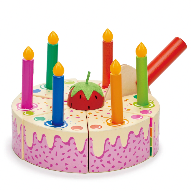 Toy birthday cake with candles and a strawberry on a white background