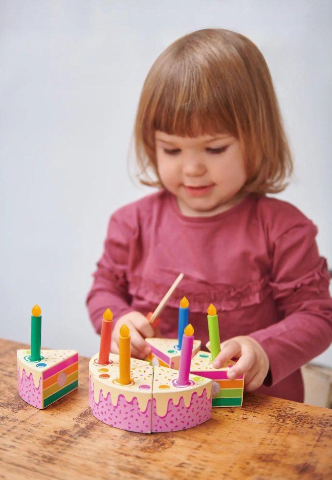 Child playing with a colorful toy cake on a wooden table