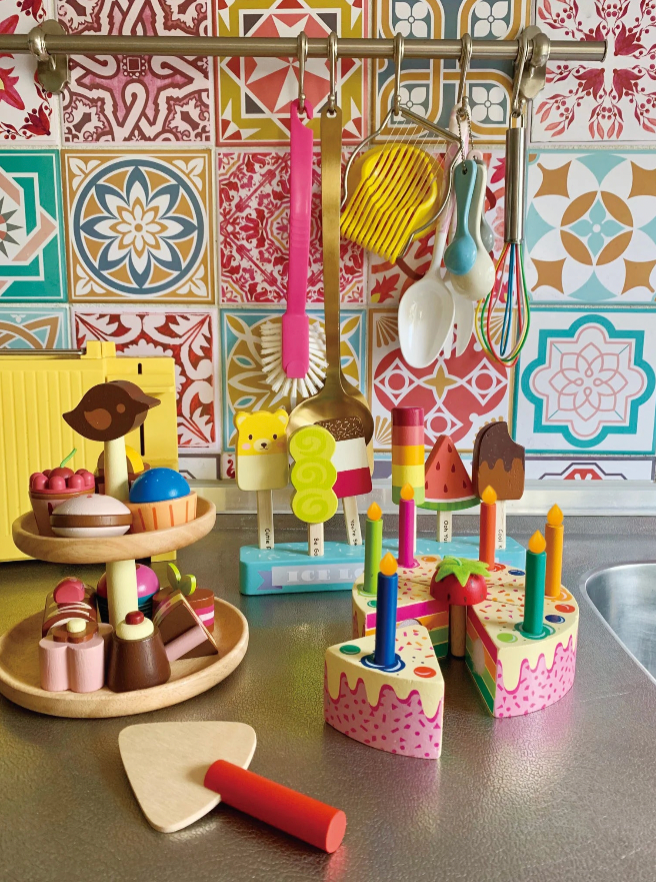 Colorful toy kitchen set on a countertop with a patterned wall in the background