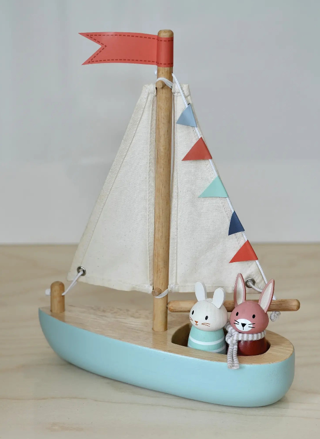 Toy sailboat with two rabbits on a wooden surface