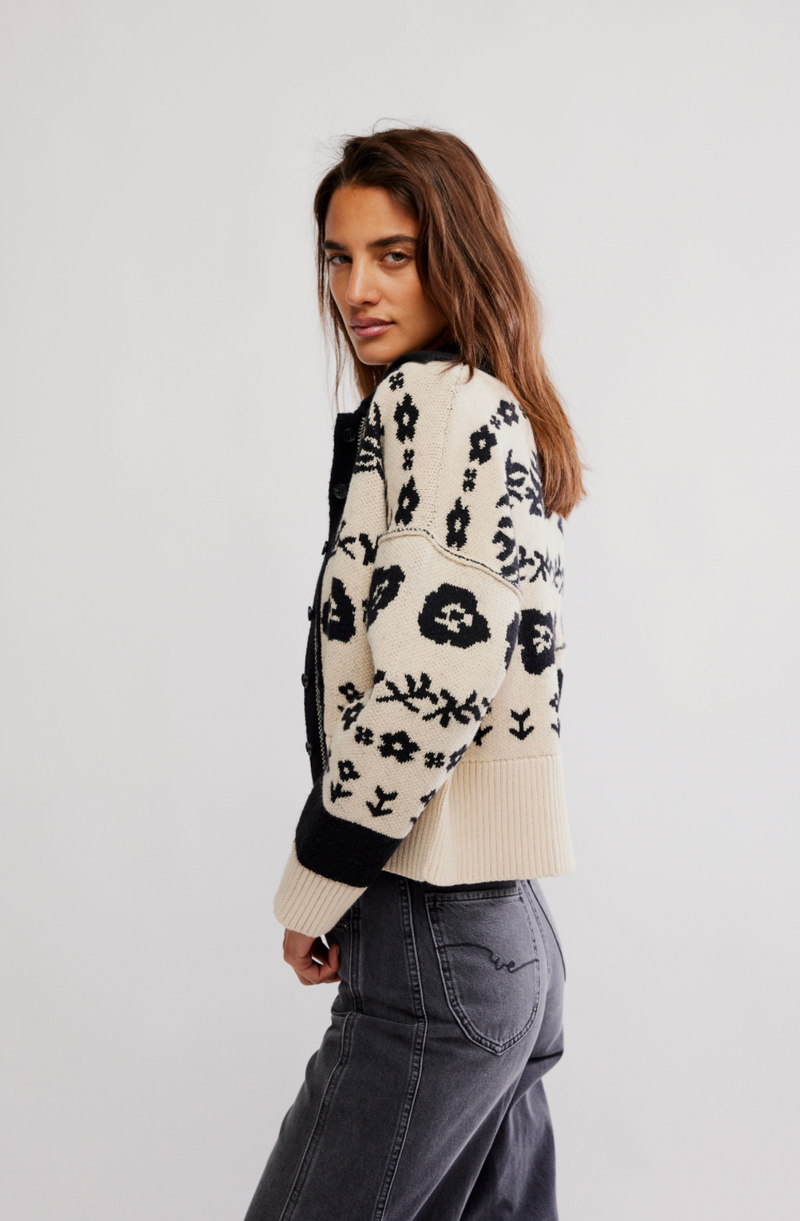 Person wearing a floral-patterned cardigan on a plain background