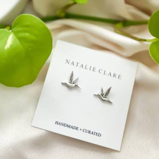 Silver bird earrings on a 'Natalie Clare' branded card with green leaves in the background
